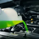 Se vierte líquido refrigerante verde en el motor de un coche. El líquido refrigerante sirve para mantener la temperatura del motor.
