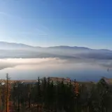 Mglisty poranek nad zbiornikiem Sosnówka. W oddali góry, a na pierwszym planie jesienny las.