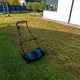 Wertykulacja trawnika w toku. Aerator pozostawił na trawie warstwę ściółki, przygotowując ją do lepszego wzrostu.