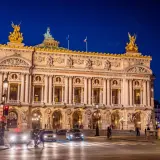 Słynny teatr w Paryżu, Opera Garnier, lśni w nocnym świetle. Złote rzeźby i bogata fasada zapraszają na wieczór pełen wrażeń.
