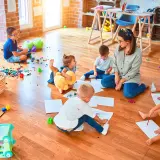 Niños de guardería de 2 años dibujan y juegan en el suelo.