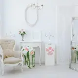 Eleganckie wnętrze w stylu shabby chic: kremowa sofa, wazon z kwiatami, lustro i świeczniki tworzą romantyczną atmosferę.