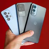 Dłoń trzyma trzy smartfony: jasnoniebieski, szary i ciemnoszary z logo Motorola. Kraj pochodzenia tej marki to USA.