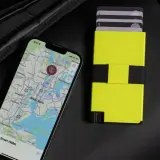 Ein Smartphone mit Karte von New York und ein gelbes Kartenetui liegen neben einem schwarzen Rucksack. Perfekt, um bargeldlos zu bezahlen.