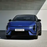 Niebieski Kia EV4 GT-Line, elektryczny sedan, prezentuje się nowocześnie przed budynkiem.