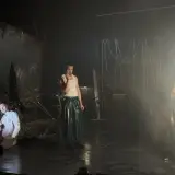 Trzej aktorzy na scenie, jeden klęczy, drugi stoi w błyszczącej spódnicy, trzecia w połyskującej sukni. Scenografia sugeruje **epic the musical**.