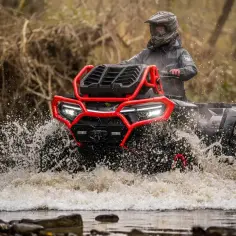 Kierowca w kasku i kurtce przemierza wodę na quadzie CF Moto, który zdecydowanie warto zabrać na terenowe wyprawy.