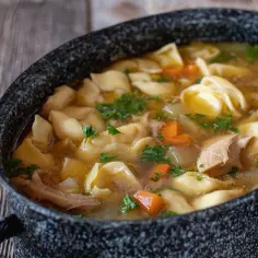 Gorąca zupa z makaronem, kawałkami kurczaka i marchewką, posypana natką pietruszki. Czy zupa to obiad? Zdecydowanie tak!