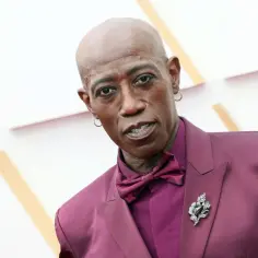 Wesley Snipes, jeden z wybitnych ciemnoskórych aktorów, w bordowym garniturze i z broszką w kształcie kwiatu.