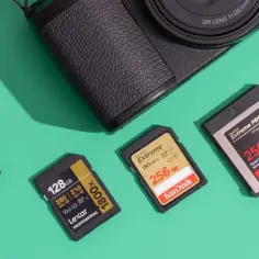 Karta flash SanDisk Extreme PRO 256 GB obok innych kart pamięci i fragmentu aparatu.