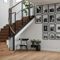 Galeria czarno-białych zdjęć na ścianę przy schodach. Drewniane stopnie i nowoczesna balustrada tworzą elegancką przestrzeń.