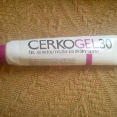 Biała tubka z napisem CERKOGEL 30, żel keratalityczny do skóry głowy, na brązowym tle.