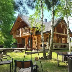 Drewniany dom w lesie, idealne żarki letnisko. Krzesła i stół zapraszają do odpoczynku.