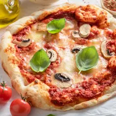 Pyszna pizza wegańska z pieczarkami, pomidorami i bazylią. Składniki tej pysznej pizzy wyglądają apetycznie.