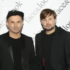 Dwóch mężczyzn w czarnych ubraniach. Jeden z nich, Andrzej Wierzbicki fryzjer, ma na głowie czapkę z daszkiem.