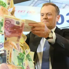 Donald Tusk z talerzem pełnym banknotów euro, symbolizującym przyszłość euro w Polsce.