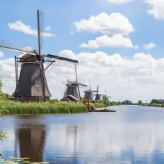 Wiatraki w Kinderdijk, jedne z najpiękniejszych miejsc w Holandii, odbijają się w spokojnej wodzie kanału.