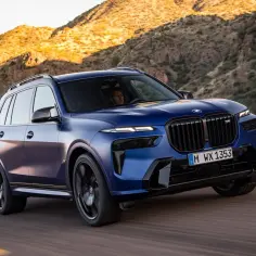 Niebieski BMW X9 pędzi przez pustynny krajobraz.