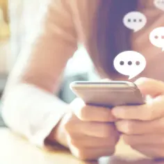 Osoba pisze na telefonie, a nad nim pojawiają się dymki czatu. Dowiedz się, jak włączyć dymki czatu w Messengerze, by rozmowy były jeszcze bardziej widoczne.