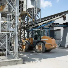 Ładowarka pracuje przy betonarni, gdzie można dowiedzieć się, jak obliczyć kubik betonu.