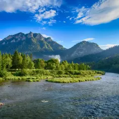 Malowniczy widok na Dunajec i góry, idealne miejsce na polskie wakacje. Zielone łąki, lasy i skaliste szczyty tworzą zapierający dech w piersiach krajobraz.