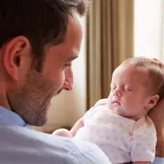 Ojciec trzyma śpiące dziecko. Pytanie, czy hermafrodyta może mieć dzieci, jest złożone i zależy od indywidualnych czynników biologicznych.