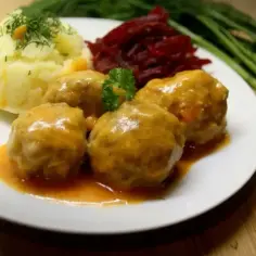 Pulpeciki w sosie z ziemniakami i buraczkami na białym talerzu.