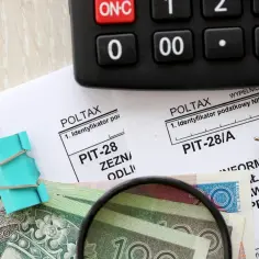 Zestaw do rozliczenia PIT-28/A: formularze, kalkulator, pieniądze i lupa. Przygotowanie do złożenia deklaracji podatkowej.