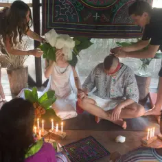 Ceremonia ślubna w Peru: para siedzi na podłodze, otoczona świecami i liśćmi, podczas gdy inni uczestnicy biorą udział.