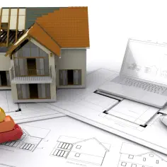Model domu w budowie, plany architektoniczne, laptop i wskaźnik efektywności energetycznej. Pasywny co to znaczy? To dom energooszczędny.