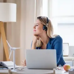 Pracownica na home office w słuchawkach, myśląca o zwrocie ryczałtu za koszty prądu i internetu.