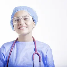 Uśmiechnięta pielęgniarka w czepku i fartuchu, z różowym stetoskopem. Zastanawiasz się, ile zarabia pielęgniarka w szkole?