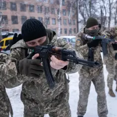 Mężczyźni w mundurach ćwiczą strzelanie z karabinów, przygotowując się na wybuch wojny na Ukrainie.