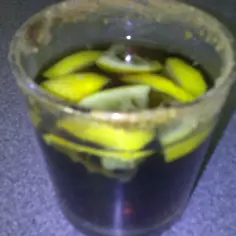Szkło z drinkiem Malibu z colą, ozdobione plasterkami cytryny i cukrowym rantem.
