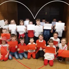 Dzieci świętują dzień flagi, trzymając białe i czerwone kartki.