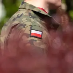 Żołnierz w mundurze moro z polską flagą na ramieniu, symbol służby i przyszłej emerytury wojskowej.