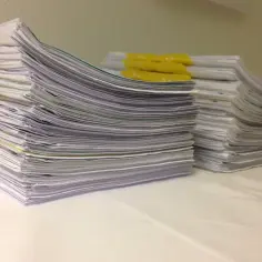 Stosy dokumentów, w tym te z żółtymi przekładkami, czekają na rozpatrzenie. Wśród nich znajduje się orzeczenie o potrzebie kształcenia specjalnego.