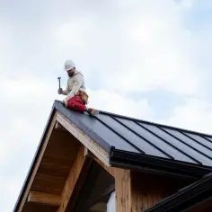 Budowlaniec na dachu montuje nowoczesną folię na dach zamiast papy.