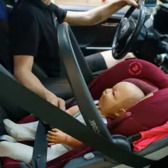 Fotelik dziecięcy z manekinem zamontowany z przodu samochodu za pomocą systemu isofix.