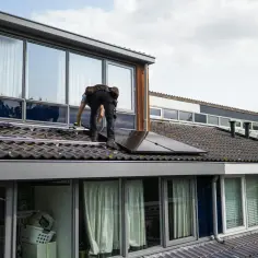 Instalator na dachu montuje panele fotowoltaiczne. Kluczowe jest, jak obliczyć przekrój kabla do mocy, by instalacja działała bezpiecznie i efektywnie.