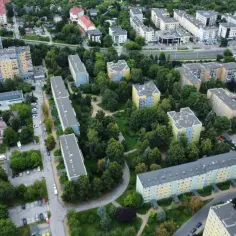 Osiedle z blokami mieszkalnymi, drzewa i drogi. Widok z lotu ptaka na ceny mieszkań w Lublinie.