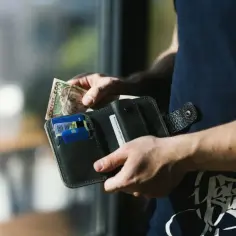 Ręce wkładają banknot 500 hrywien do portfela. Kto płaci pośrednikowi przy sprzedaży mieszkania? Prawdopodobnie sprzedający.