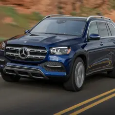 Granatowy Mercedes GLS 580 pędzi po pustynnej drodze, otoczony suchymi wzgórzami.