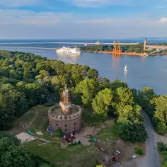 Karsibór atrakcje: okrągła twierdza z wieżą widokową otoczona zielenią, w tle port i prom.