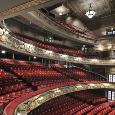Eleganckie wnętrze teatru z czerwonymi fotelami i złotymi zdobieniami. Idealne miejsce, by sprawdzić, na co warto iść do teatru w Warszawie.