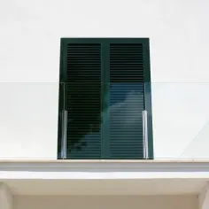 Nowoczesny balkon z przeszkloną balustradą. Okapnik nad drzwiami balkonowymi zapewnia ochronę przed deszczem.