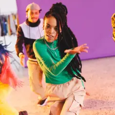 Grupa młodych ludzi tańczy w rytm dancehallu. Energetyczne ruchy i kolorowe stroje tworzą radosną atmosferę.