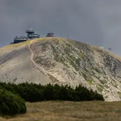 Karkonosze szczyty z budynkami obserwatorium i kolejką linową na tle pochmurnego nieba.