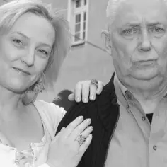 Joanna Kossowska i starszy mężczyzna pozują do zdjęcia. Wiek Joanny Kossowskiej nie jest widoczny, ale widać jej uśmiech.
