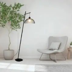 Nowoczesna, czarna stojąca lampa led z metalowym kloszem, oświetlająca przytulny kącik z fotelem i rośliną.